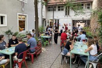 Menschen sitzen in einem gemütlichen Innenhof an Tischen und unterhalten sich.