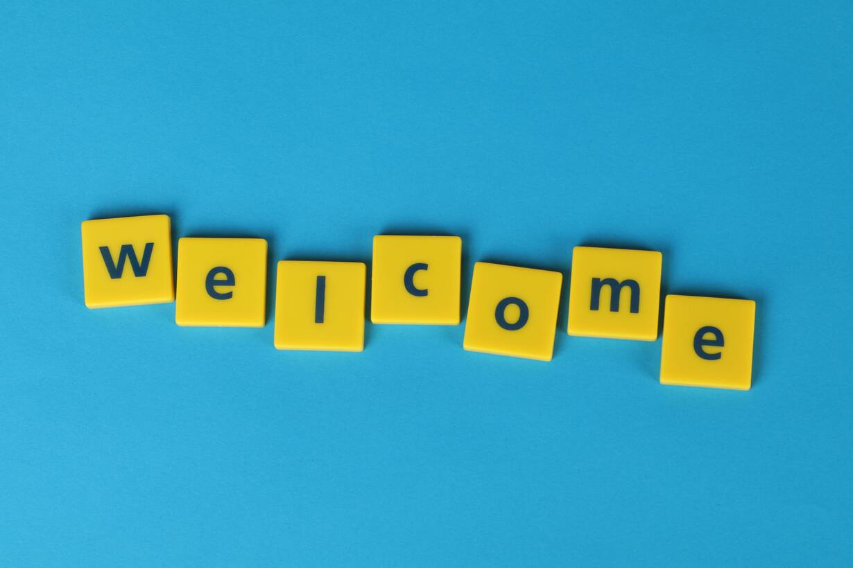 Gelbe Buchstabensteine bilden das Wort „Welcome“ auf blauem Hintergrund.