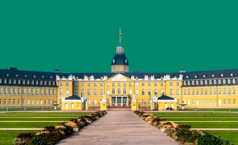 Frontansicht des gelben Schlosses in Karlsruhe mit zentralem Turm und symmetrischer Gartenanlage.