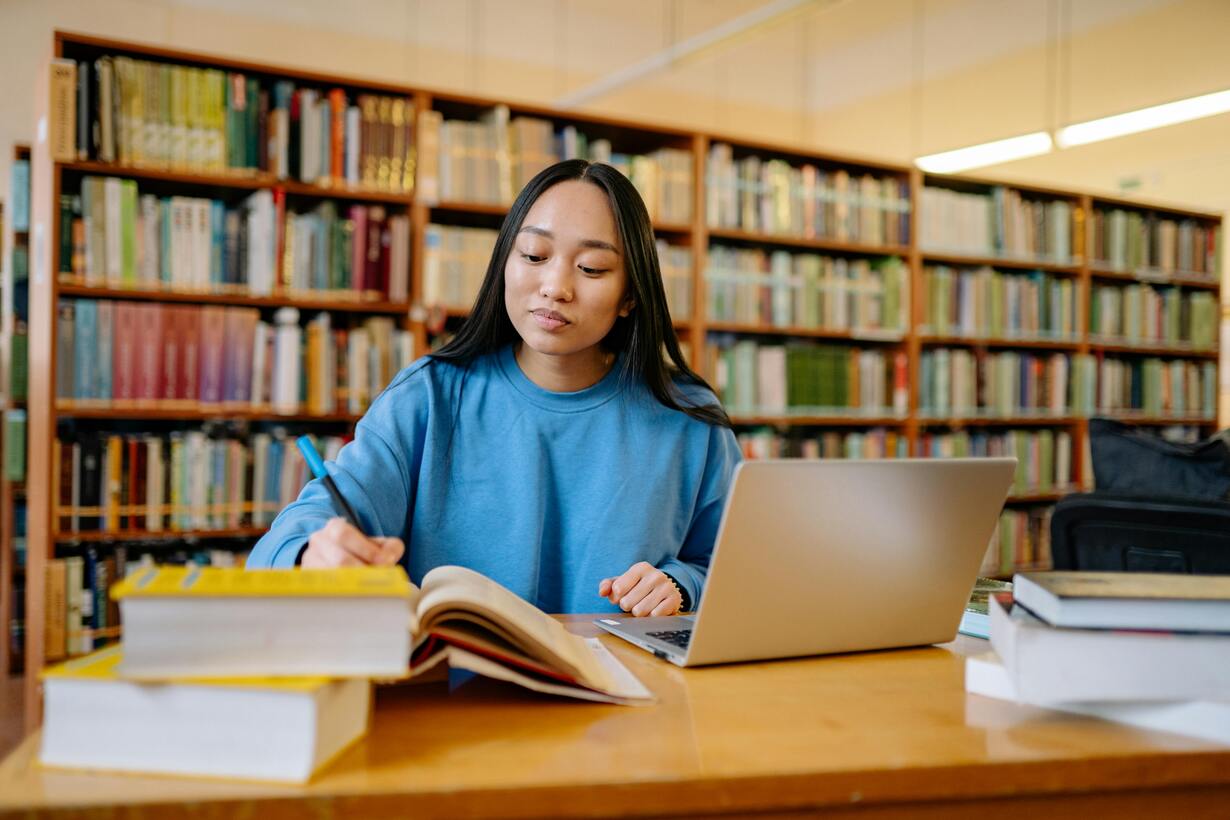 Frau am lernen in Bibliothek vor Bücherregal